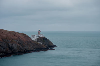 Lighthouse by sea against sky