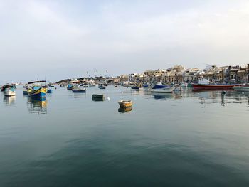 Boats moored in harbor against sky