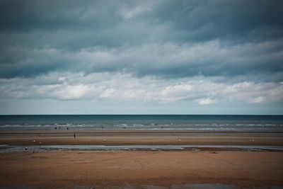 Scenic view of beach against cloudy sky