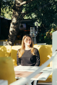 Portrait of a smiling young woman sitting on table