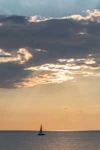 Sailboat in sea against sky during sunset