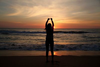 Silhouette woman standing at beach during sunset