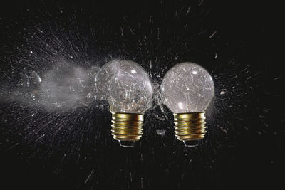 Close-up of illuminated light bulb against black background