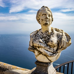 Statue by sea against sky