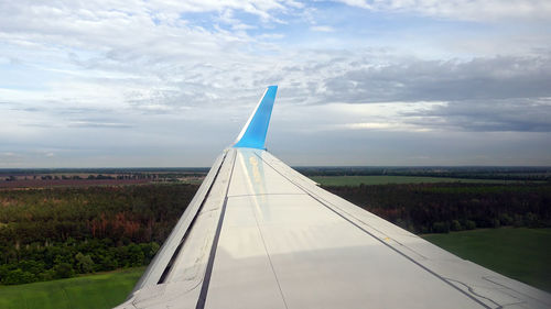 Airplane flying over landscape against sky