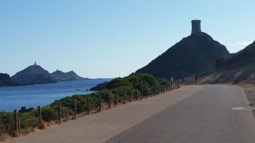 Scenic view of road by mountains against clear sky