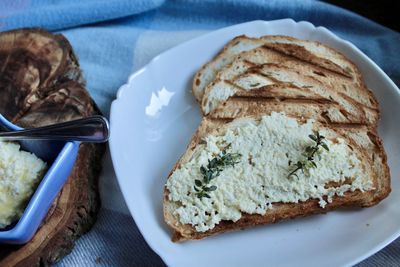 Sandwiches from a loaf and with cheese paste on a wooden stand and in a white plate