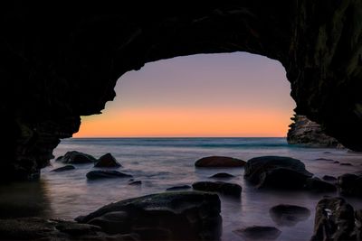 Scenic view of sea seen from cave against sky during sunset