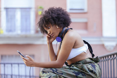 Side view of woman listening music while sitting outdoors