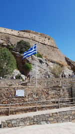 Low angle view of flag on built structure against blue sky