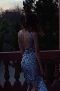 Rear view of woman standing against railing