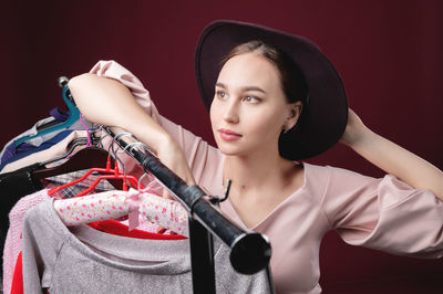 Portrait of young woman holding red face against black background