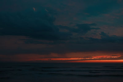 Scenic view of sea against dramatic sky during sunset