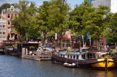 Boats moored in canal by trees