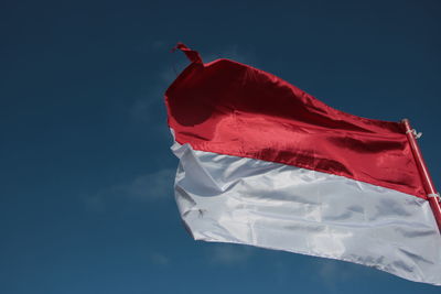 Low angle view of flag against blue sky