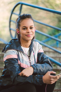 Portrait of young woman listening music through mobile phone on stairs