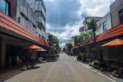 Empty road amidst buildings in city against sky