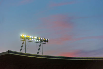 Glowing stadium lights against sunset sky during blue hour