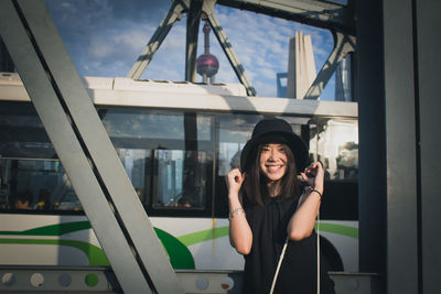 Portrait of smiling young woman standing against built structure in city