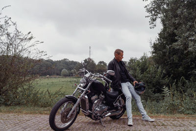 Man riding motorcycle on road against sky