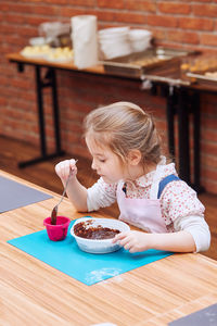 Close-up of cute girl eating food at table at home