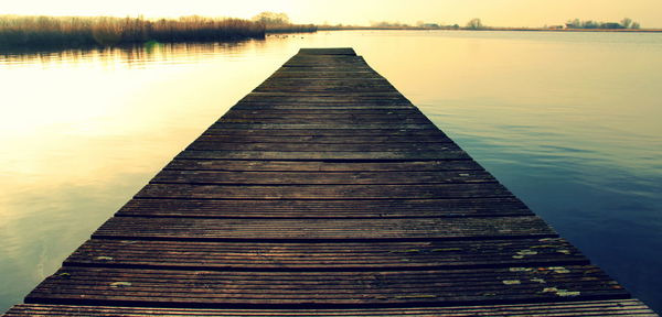 Wooden pier over lake during sunset