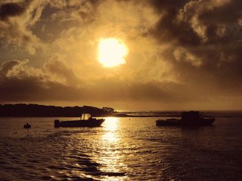 Silhouette boat sailing in sea against sky during sunset