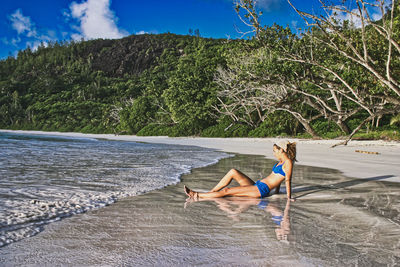 Side view of woman on beach against sky