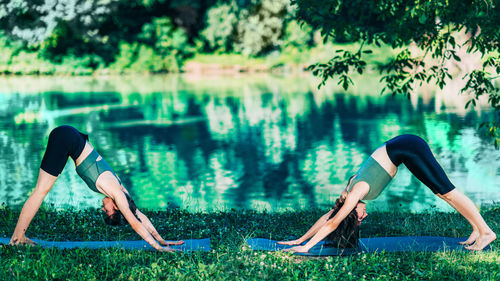 Yoga women by the lake. downward facing dog pose