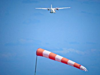 Low angle view of airplane and windsock flying against sky