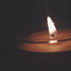 Close-up of lit candle in dark room