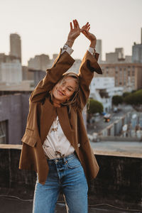 Midsection of young woman standing in city against sky