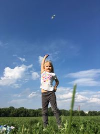 Full length of happy girl playing on field against sky