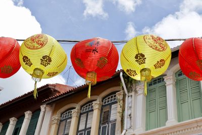 Low angle view of red and yellow chinese lanterns hanging against building