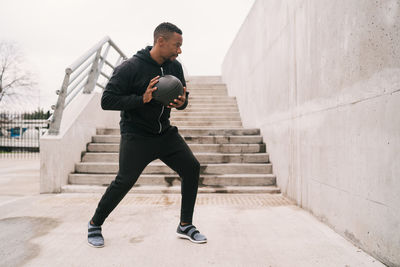 Full length of man exercising with medicine ball against wall