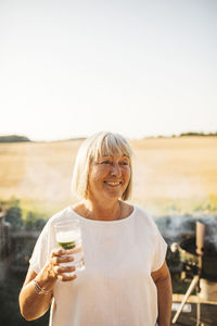 Smiling woman in garden holding drink