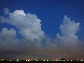 View of illuminated cityscape against cloudy sky