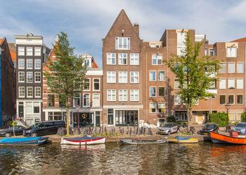 Boats moored in canal by buildings in city