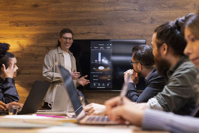 Happy businessman giving presentation to colleagues during meeting in board room