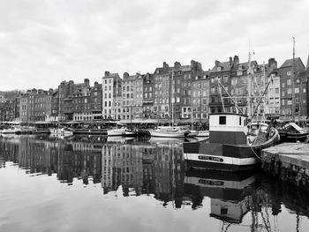 Boats moored at harbor against buildings in city