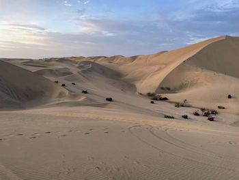 Scenic view of desert with sand buggies against sky