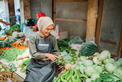 Portrait of smiling man holding vegetables at farm