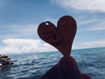 Person with heart shape in sea against sky