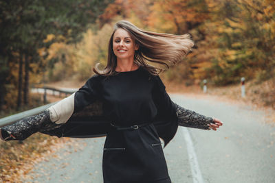 Portrait of woman standing on road during autumn