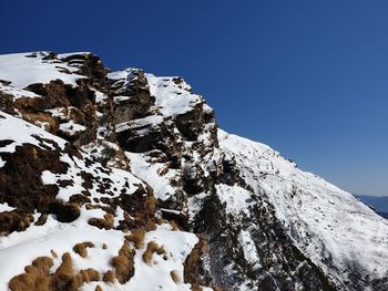 Low angle view of snowcapped mountain against blue sky