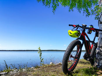 Bicycle by tree against clear blue sky