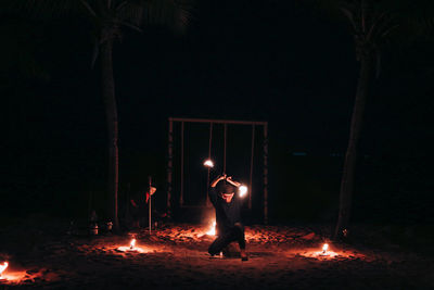 Full length of man standing against illuminated fire at night