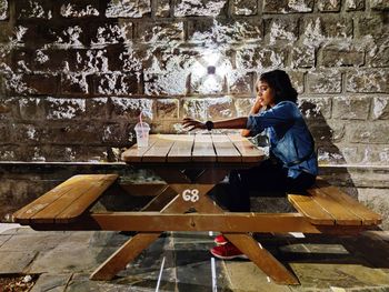Side view of girl sitting on wall