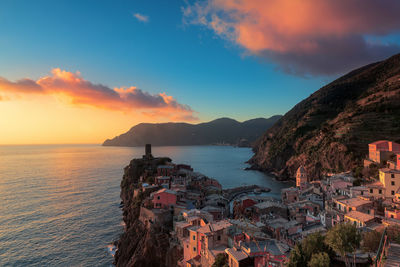 High angle view of houses by sea against sky during sunset