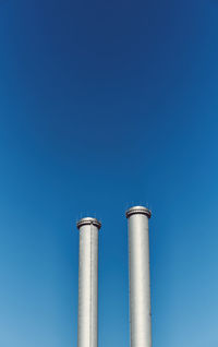 Low angle view of smoke stack against blue sky